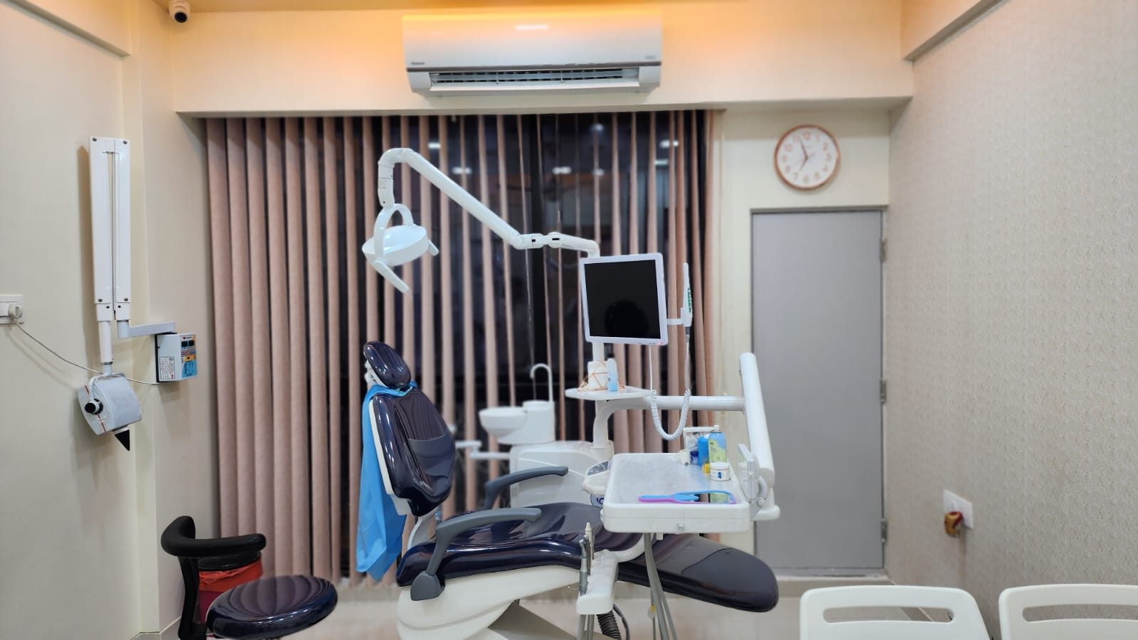 Dental chair and delivery unit in the treatment room, with a monitor and overhead light